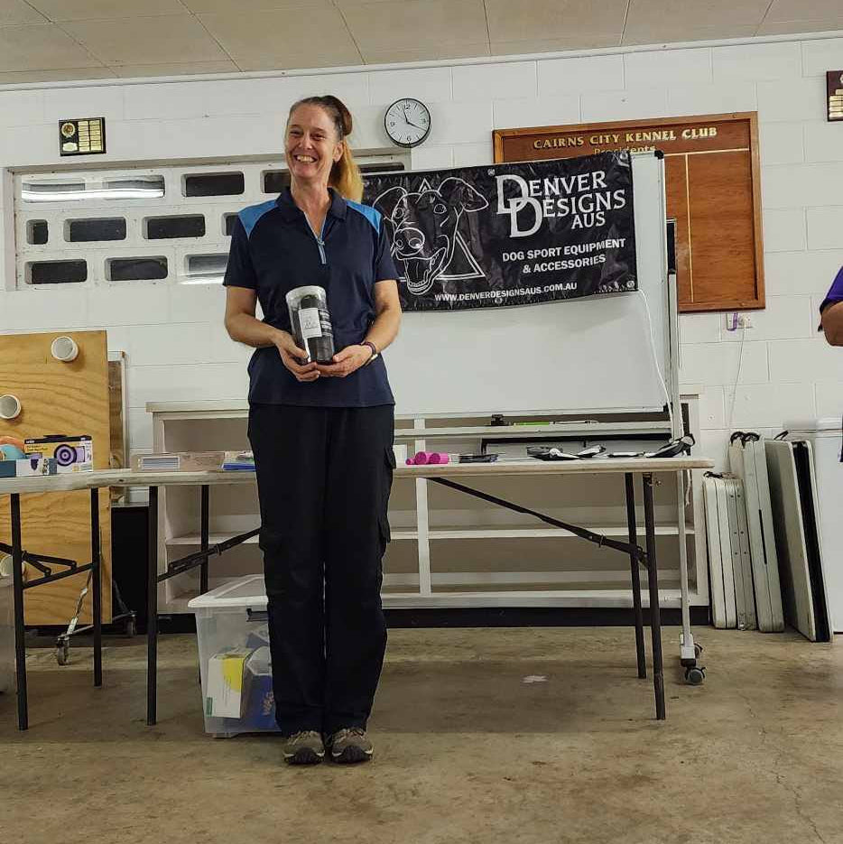 Woman standing in a room with tables and a Denver Designs banner on the wall.
