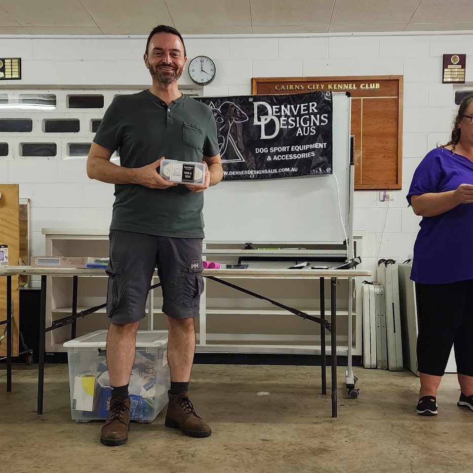 Man holding a prize in a room with tables and chairs