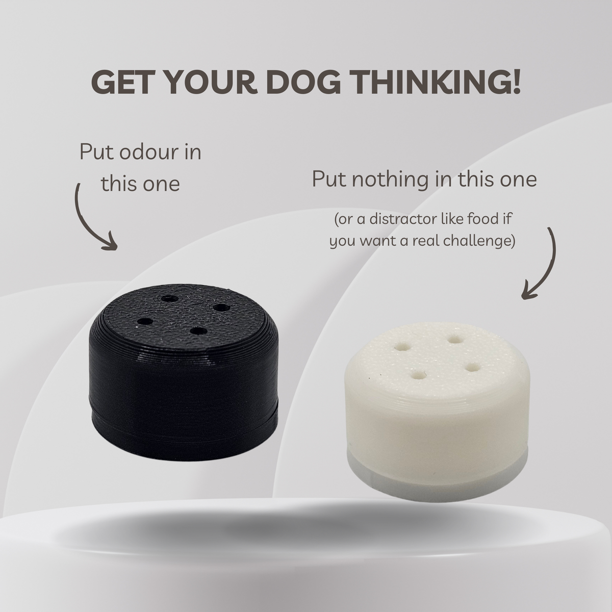 Two cylindrical dog training magnetic scent vessel shown on a light gray graphic background with explanatory text. The left device is black and labeled 'Put odour in this one,' and the right device is white and labeled 'Put nothing in this one (or a distractor like food if you want a real challenge).