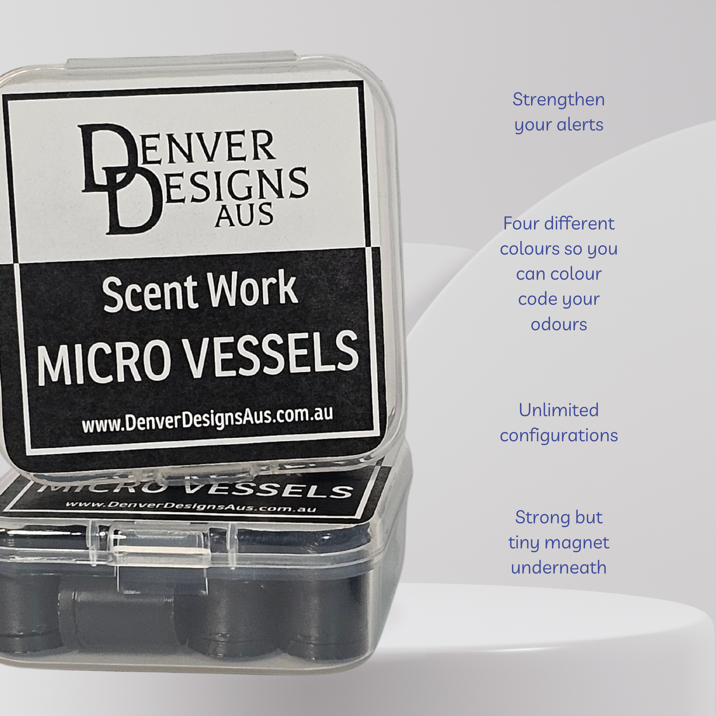 A clear plastic case containing black circular micro vessels, with a large black-and-white label reading 'Denver Designs Aus Scent Work Micro Vessels.' Blue text on the right lists features such as strengthening alerts, four different colors, unlimited configurations, and a strong but tiny magnet underneath.