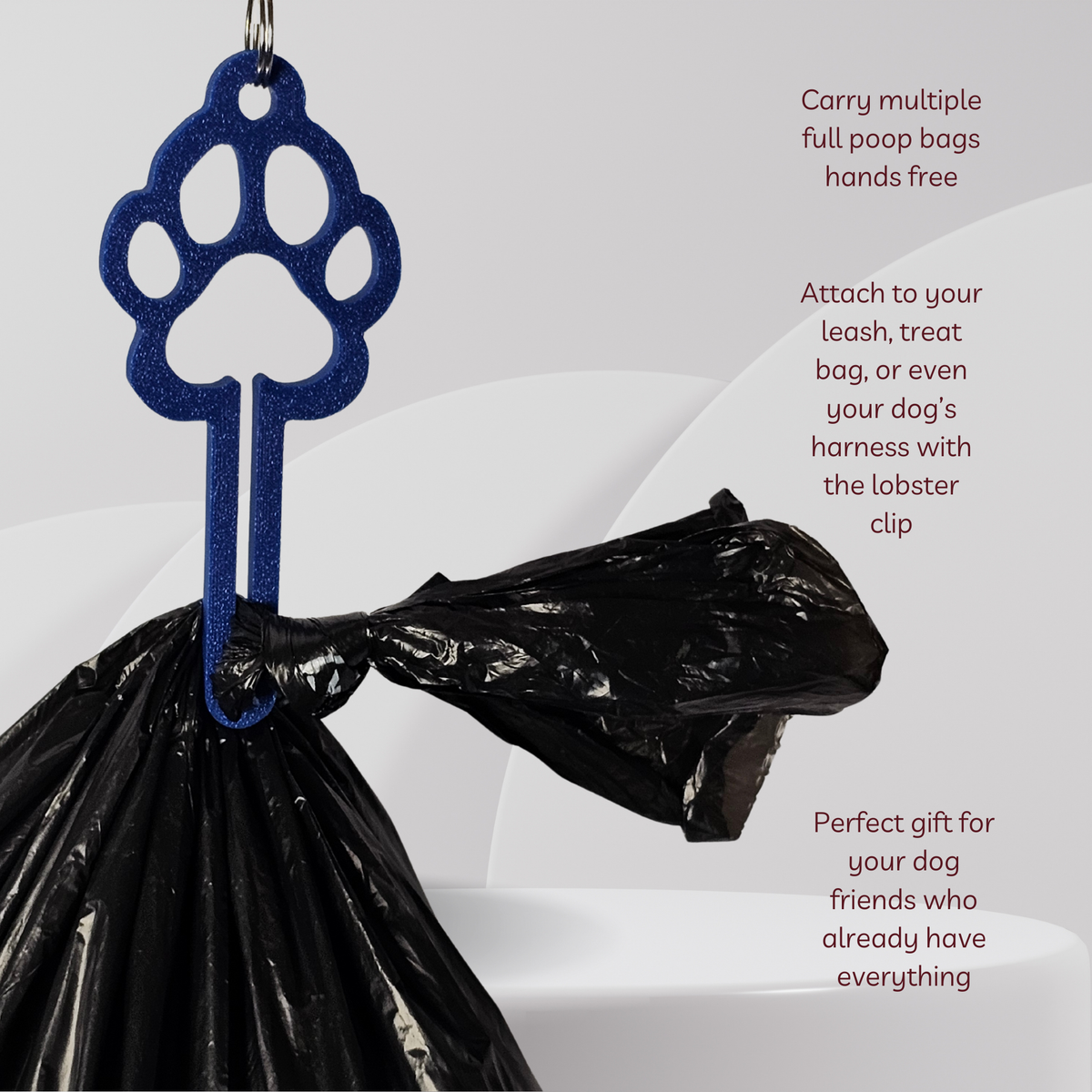 A blue paw-print shaped dog poop bag carrier clip attached to a black plastic bag, with marketing text on a light gray background.