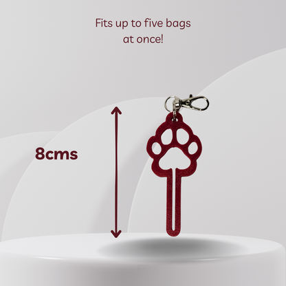 A red paw-shaped keychain bag clip with a silver clasp, shown on a light gray background with text indicating it fits up to five bags at once and a height measurement of 8cm.