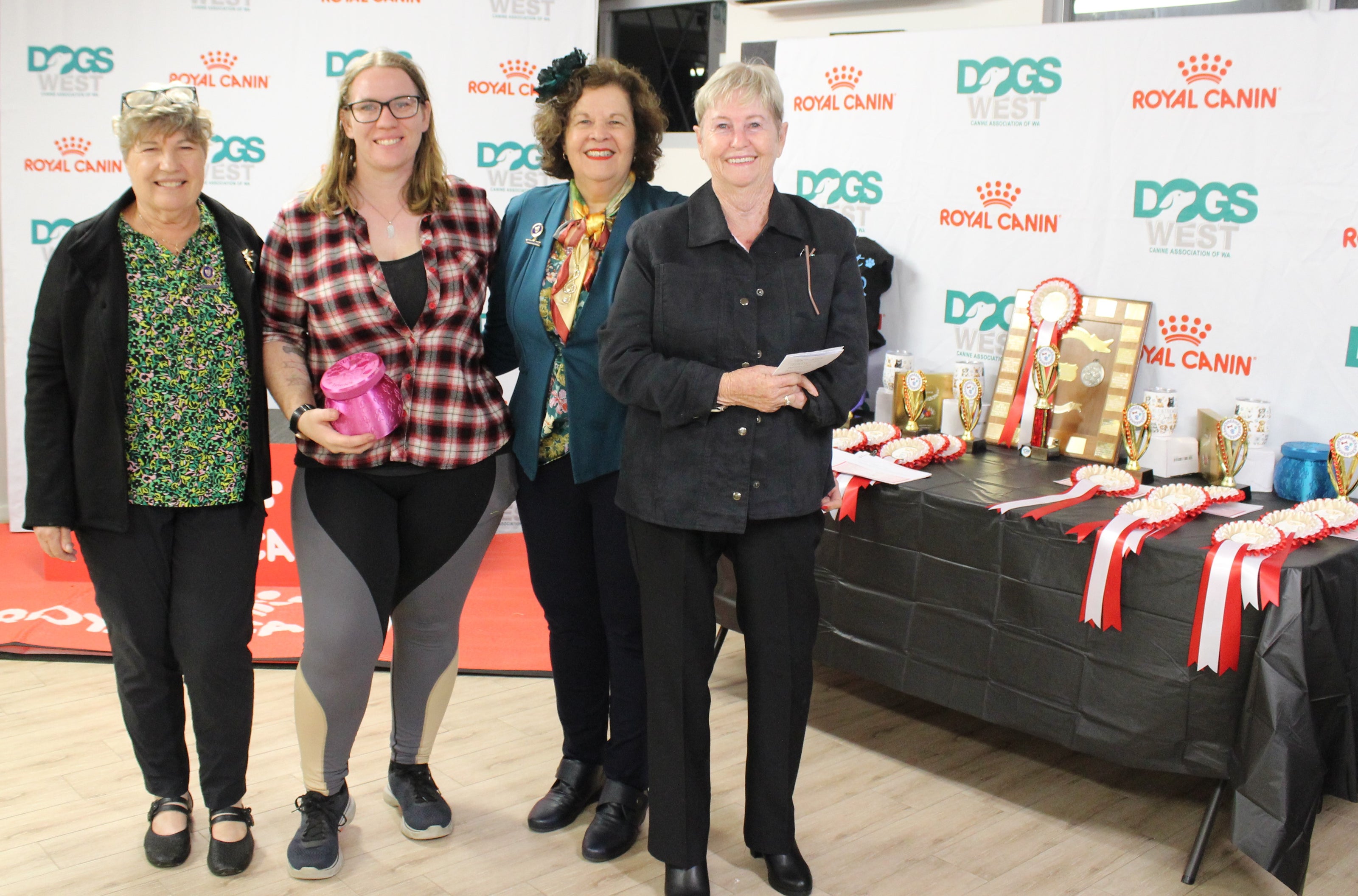Four women posing for a photo in front of a table with awards and Royal Canin branding.