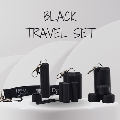 A black travel set displayed on a white pedestal, including cylindrical containers, small caps, a wrist strap with 'Denver Designs' branding, and metal keychains, with the text 'BLACK TRAVEL SET' above.