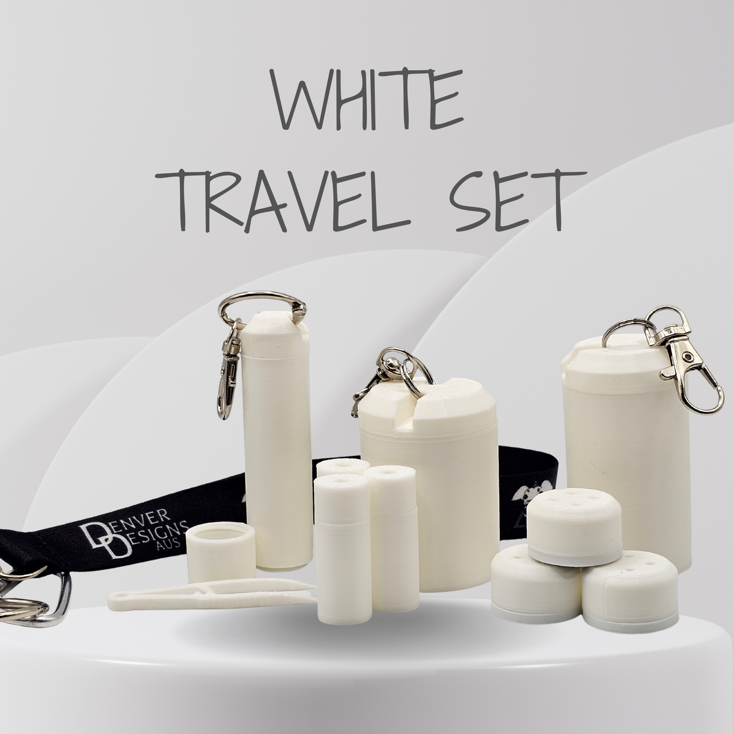 A white travel set displayed on a white surface against a light gray background with the text 'WHITE TRAVEL SET' at the top. The set includes several insulated bottle and cup containers in white, small cylindrical containers, a black branded wrist strap reading 'Denver Designs Aus', and metal keychain clips.