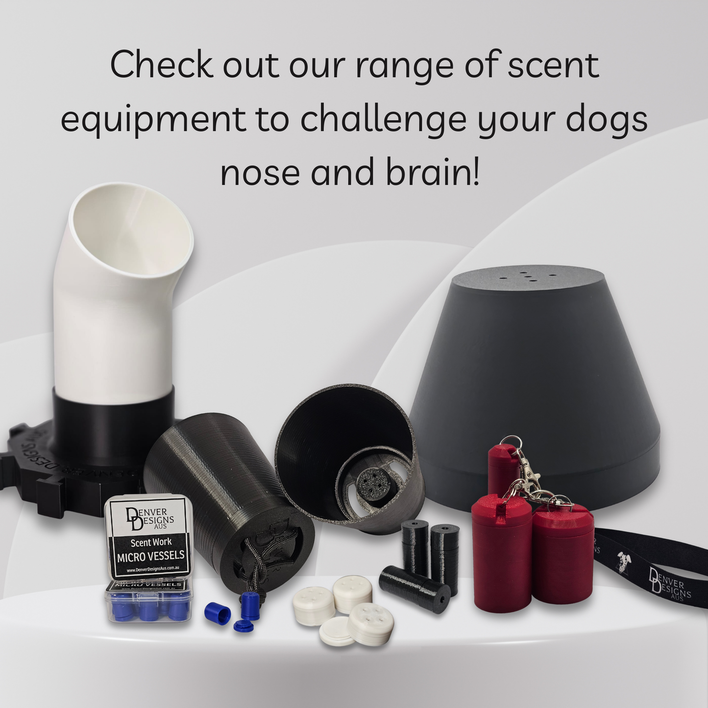 A product display of a dog scent training kit on a light gray background with text at the top. The kit includes a black and white plastic scent tube, a black cone-shaped scent dome, several black cylindrical suspended scent cups, red cylindrical vessels, white and blue micro-vessels, and a black keychain.